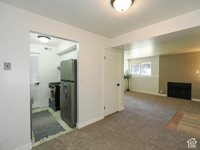 Recessed kitchen featuring stainless steel refrigerator, black range, and tile flooring