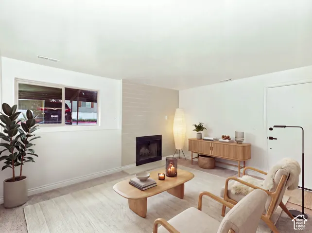 Built-in fireplace with a dark surround, light-colored brick-patterned accent wall, white walls, and a window with white trim