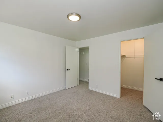 Neutral-toned carpeting, white walls, and a flush-mount ceiling light fixture