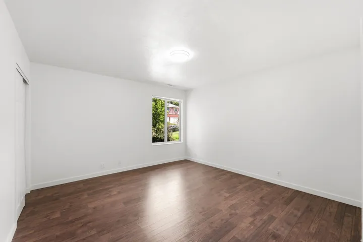 Wood-finish flooring, white walls, single window, flush-mount ceiling light
