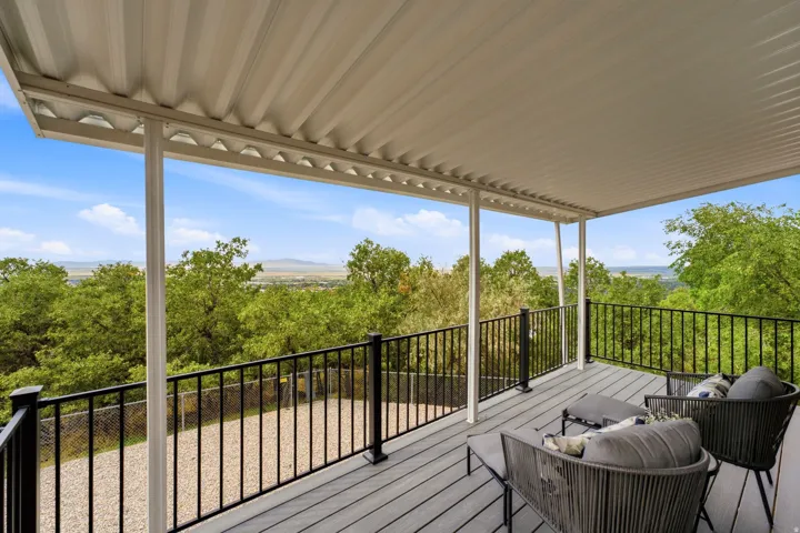 Covered outdoor deck with composite decking, black metal railings, and white support columns