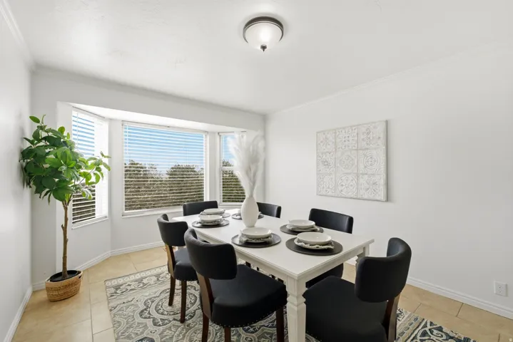 Dining area with a bay window, crown molding, a semi-flush mount ceiling fixture, and tile flooring