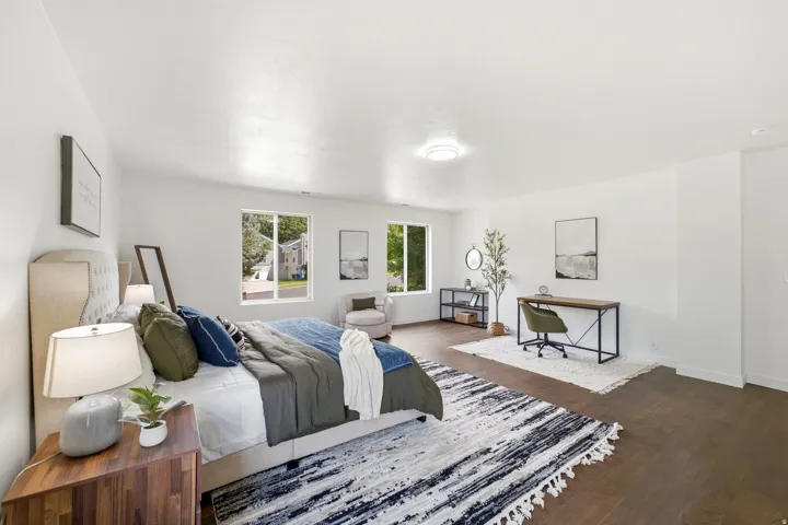Expansive room featuring rich wood-finish flooring, multiple windows, and a flush-mount ceiling light fixture