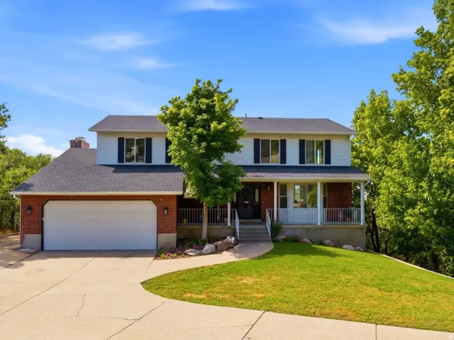 Two-story residence featuring a brick and siding exterior, front porch with columns, two-car garage, and a concrete driveway