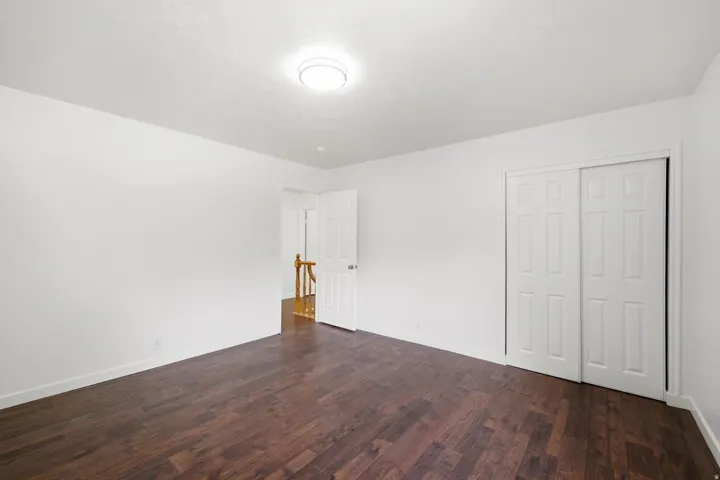 Wood-finish flooring, white walls, and a ceiling-mounted light fixture