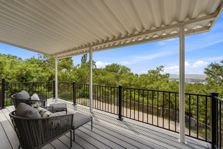 Covered outdoor deck with composite decking, supported by white structural columns and black metal railings