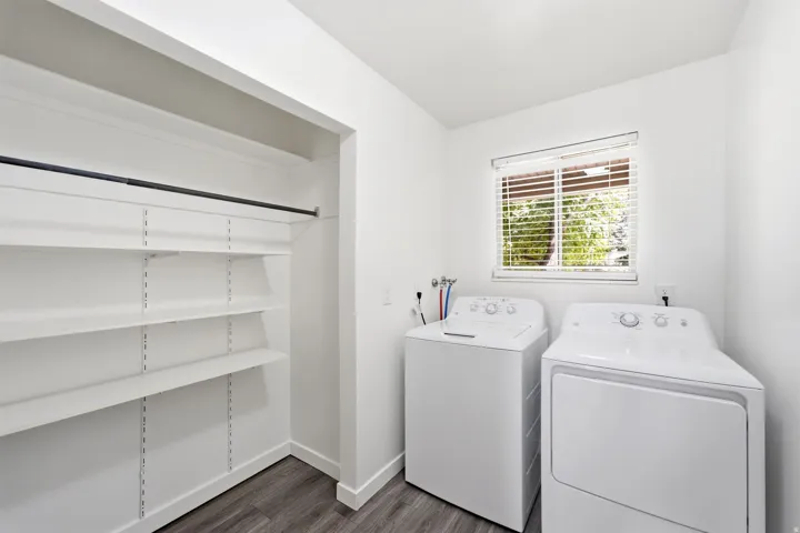 Adjustable shelving, hanging rod, wood-finish flooring, white walls, and a window with blinds