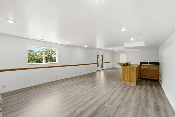 Recessed lighting, wood-finish flooring, built-in wet bar with wood cabinetry, beadboard wainscoting, and French doors
