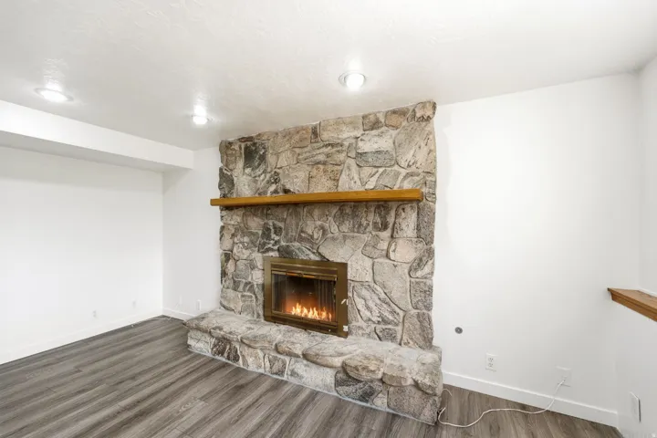 Stone-clad fireplace with a wood mantel, gas insert, and stone hearth