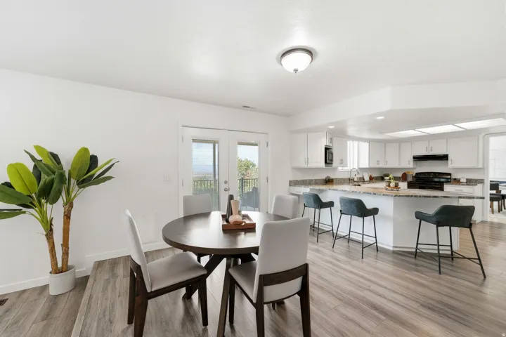Open-concept kitchen and dining area featuring wood-finish flooring, white cabinetry, and light-toned countertops