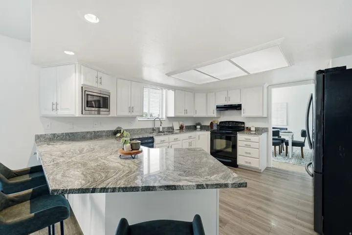 Kitchen featuring white cabinetry, a large kitchen island with a stone countertop, recessed lighting, and wood-finish flooring
