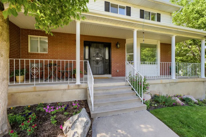 Brick facade with a full-length covered porch, white railing, and decorative entry door