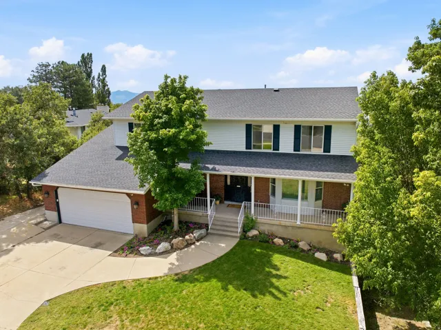 Two-story residence featuring a brick and siding exterior, front porch with white railing, attached two-car garage, and a concrete driveway