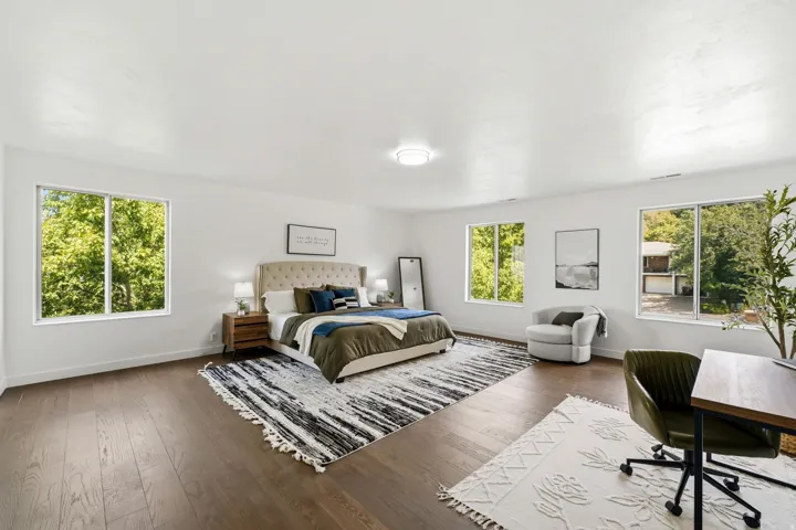 Spacious room with dark wood-finish flooring, multiple windows, and recessed lighting