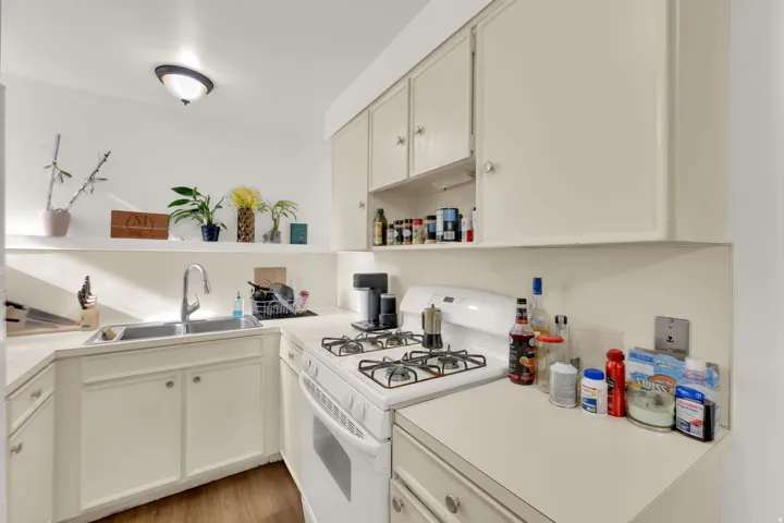 Kitchen featuring a gas range, dual-basin stainless steel sink, and light-toned cabinetry with coordinating countertops