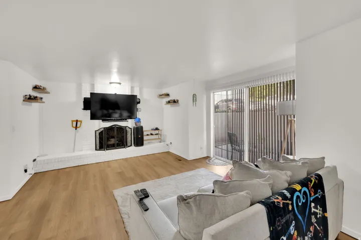 Wood-finish flooring, white brick fireplace, sliding glass door, and recessed lighting