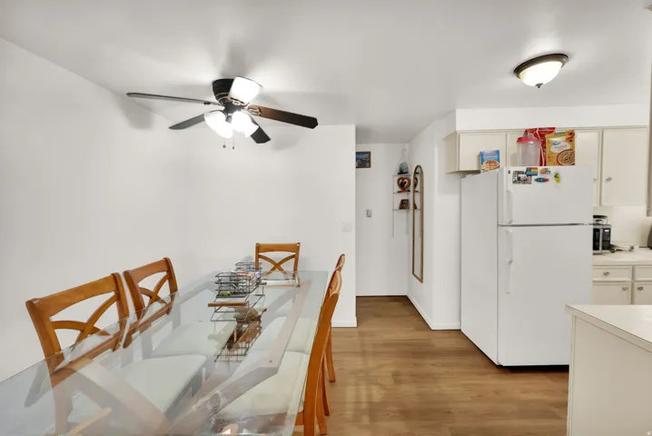 Recessed lighting, wood-finish flooring, white walls, ceiling fan with integrated lighting, white kitchen cabinetry