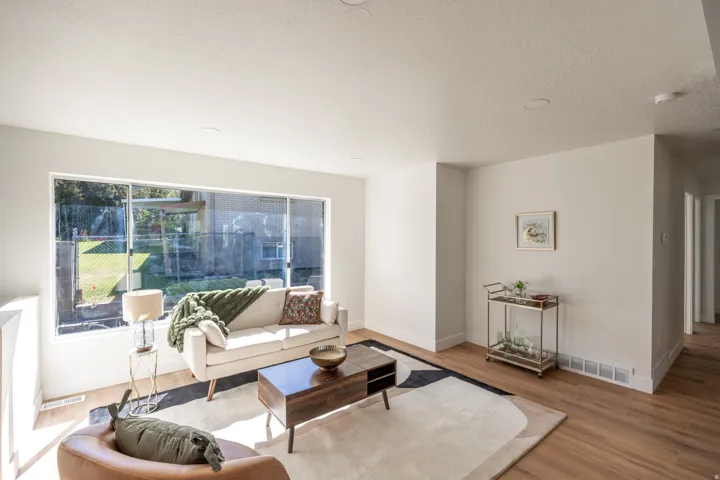 Spacious living area featuring large windows, wood-finish flooring, recessed lighting, white walls, and white baseboards