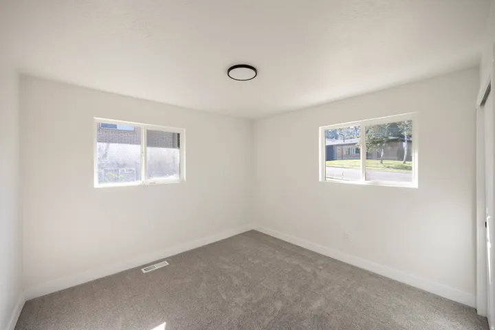 White painted walls, gray carpet, and a flush-mount ceiling light fixture