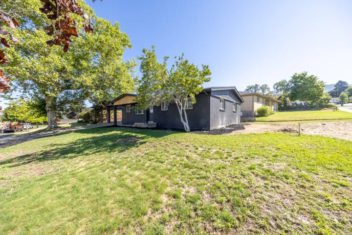 Black painted exterior with white trim windows and a natural wood-finish front door