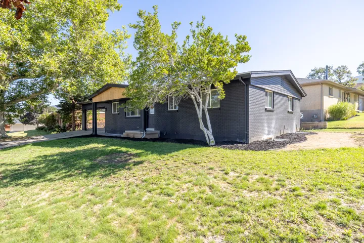 Black painted brick exterior with white trim windows and a covered entrance