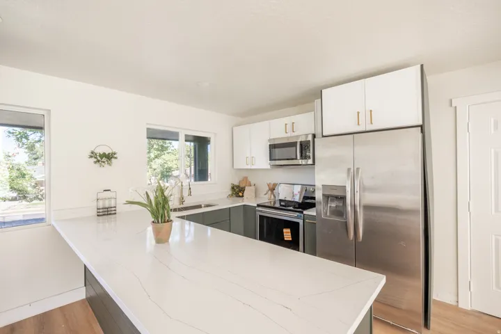 Kitchen featuring an expansive counter surface, stainless steel appliances, white upper cabinetry, and contrasting lower cabinetry