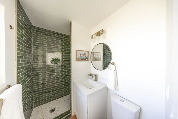 Walk-in shower with green subway tile walls and integrated niche