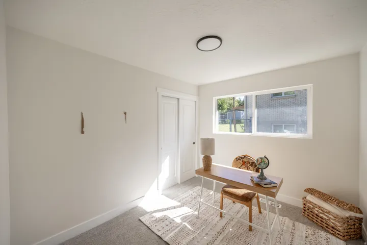 Recessed ceiling lighting, white walls, gray carpet flooring, and a single window