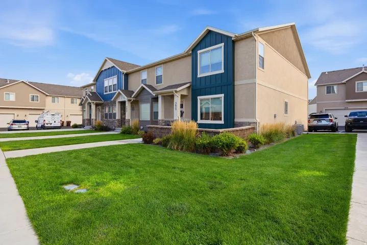Townhome exterior featuring varied siding materials, stone accents, and front landscaping