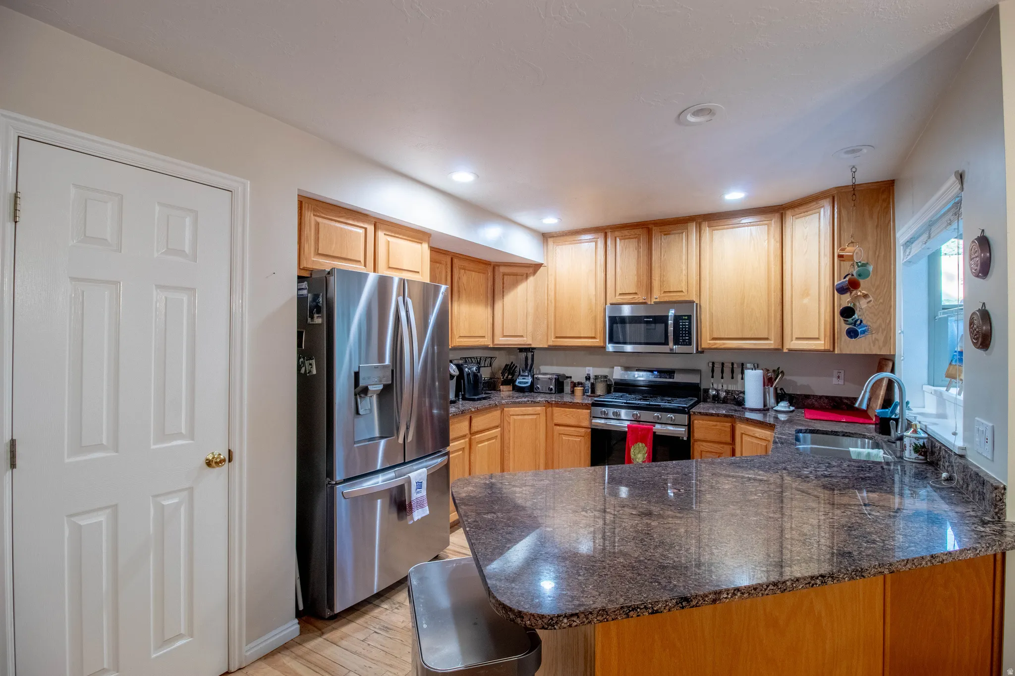 Kitchen featuring wood cabinetry, stainless steel appliances, speckled countertops, and recessed lighting