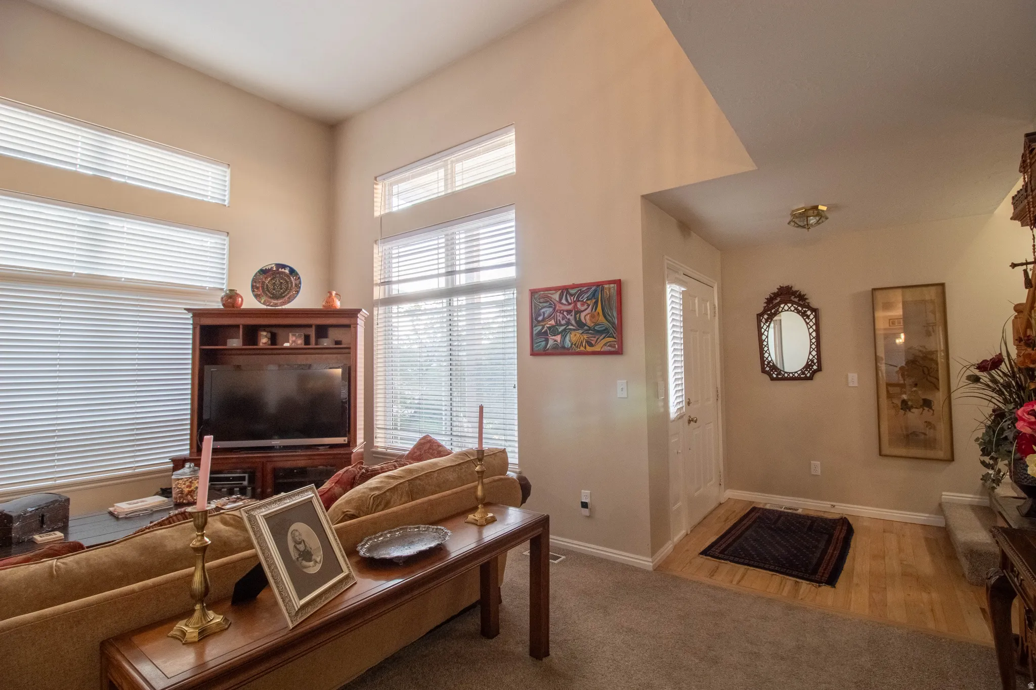 Vaulted ceiling, multiple windows with blinds, wood-finish flooring at entry, recessed entry, built-in media cabinetry