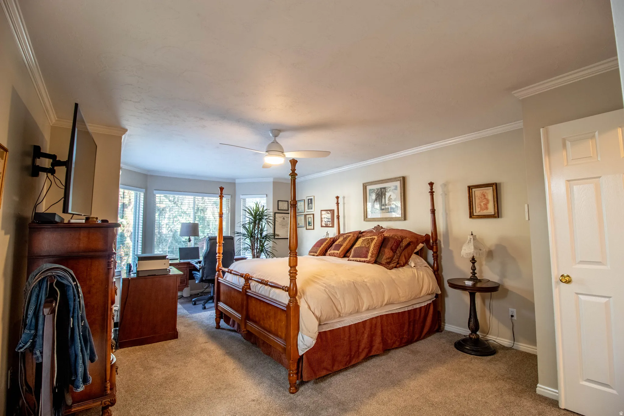 Recessed bay window, crown molding, ceiling fan, carpet flooring, and a paneled door