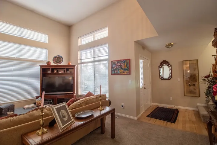 Vaulted ceiling, multiple windows with blinds, wood-finish flooring at entry, recessed entry, built-in media cabinetry