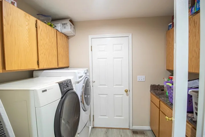 Laundry area featuring wood-finish cabinetry, a white paneled door, and wood-finish flooring