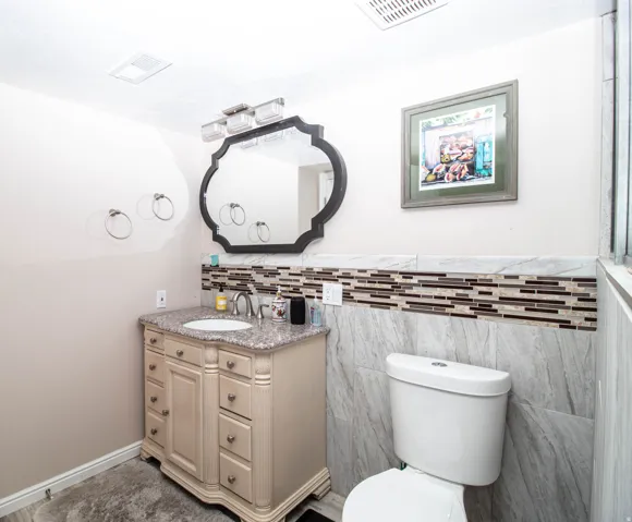 Renovated half bath featuring a custom vanity with multiple drawers and brushed nickel hardware, granite-style countertop, and chrome vessel sink