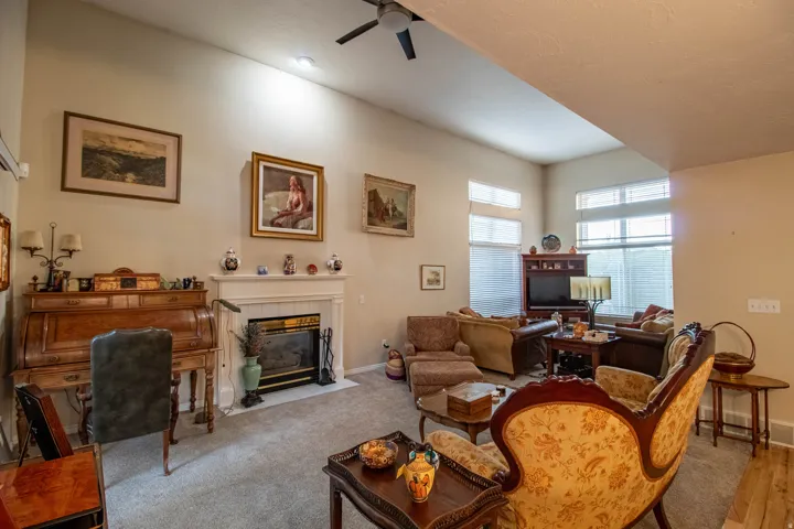 Vaulted ceilings with recessed lighting, fireplace with mantel, ceiling fan, and multiple windows with blinds