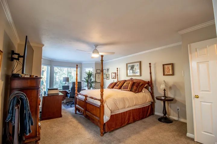 Recessed bay window, crown molding, ceiling fan, carpet flooring, and a paneled door