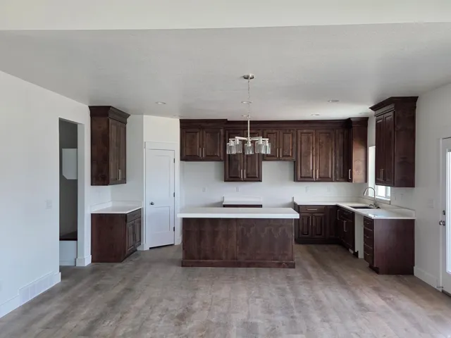 Kitchen featuring dark wood-finish cabinetry, white countertops, wood-finish flooring, and a contemporary chandelier