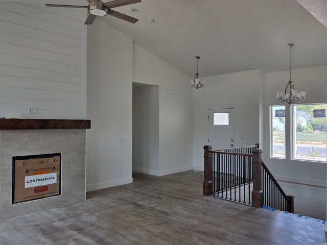Vaulted ceilings, wood-finish flooring, and a shiplap accent wall with a tiled fireplace and wood mantel
