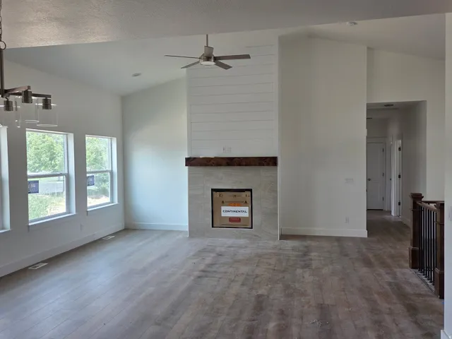 Vaulted ceilings, wood-finish flooring, and a fireplace with a wood mantle and tile surround