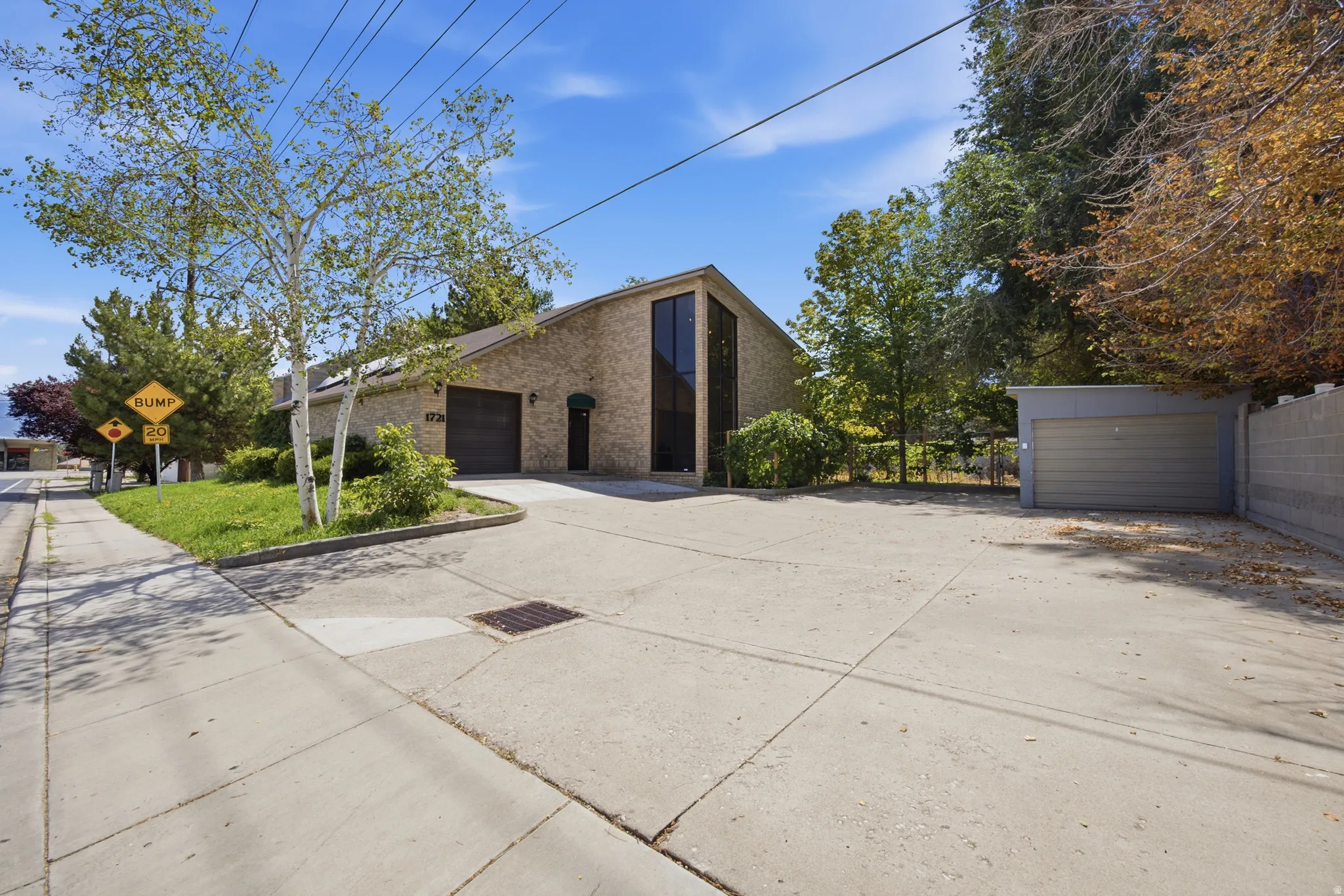 Brick exterior, attached garage, detached garage, concrete driveway, and mature landscaping