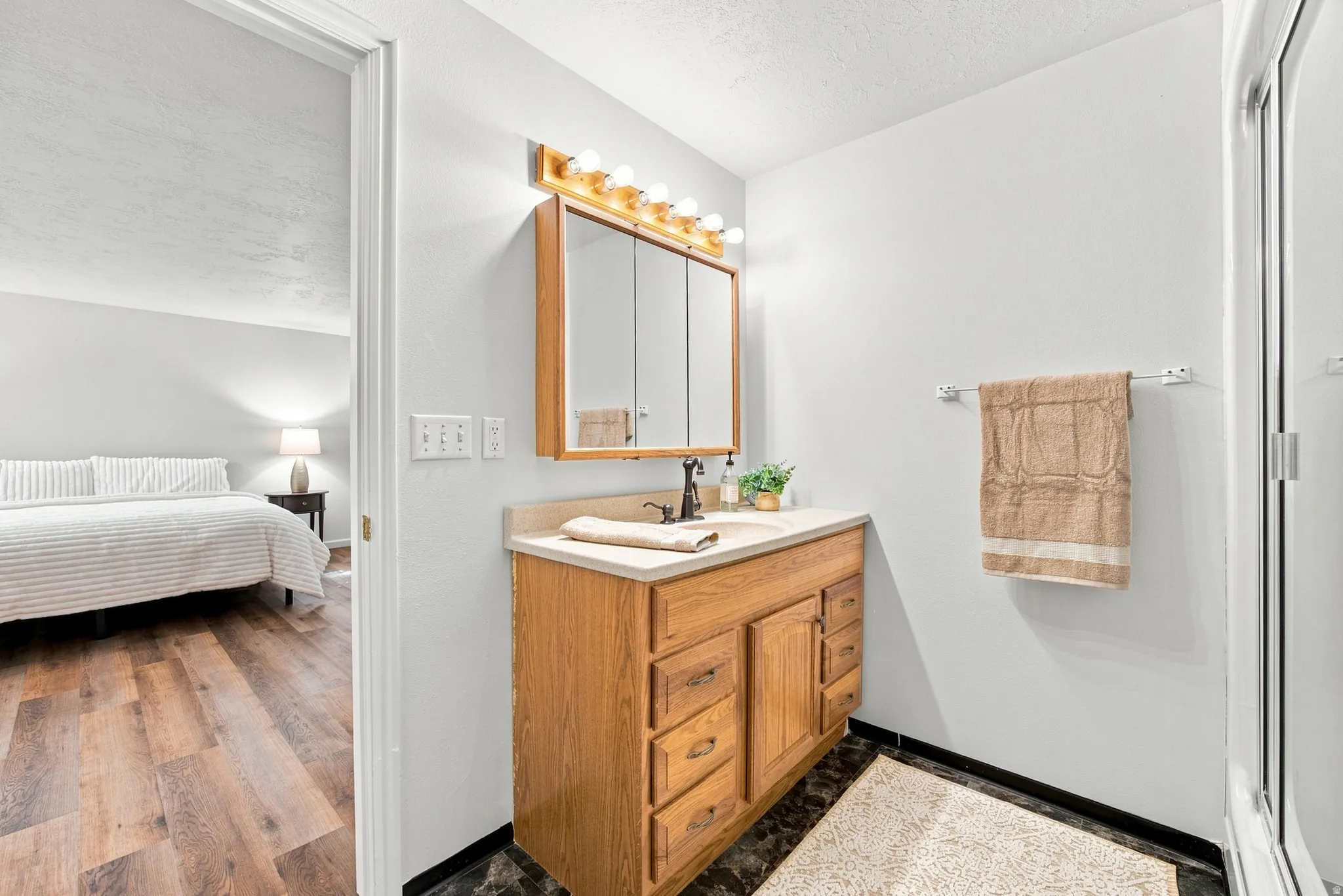 Vanity with wood-finish cabinetry, integrated sink, and light-toned countertop