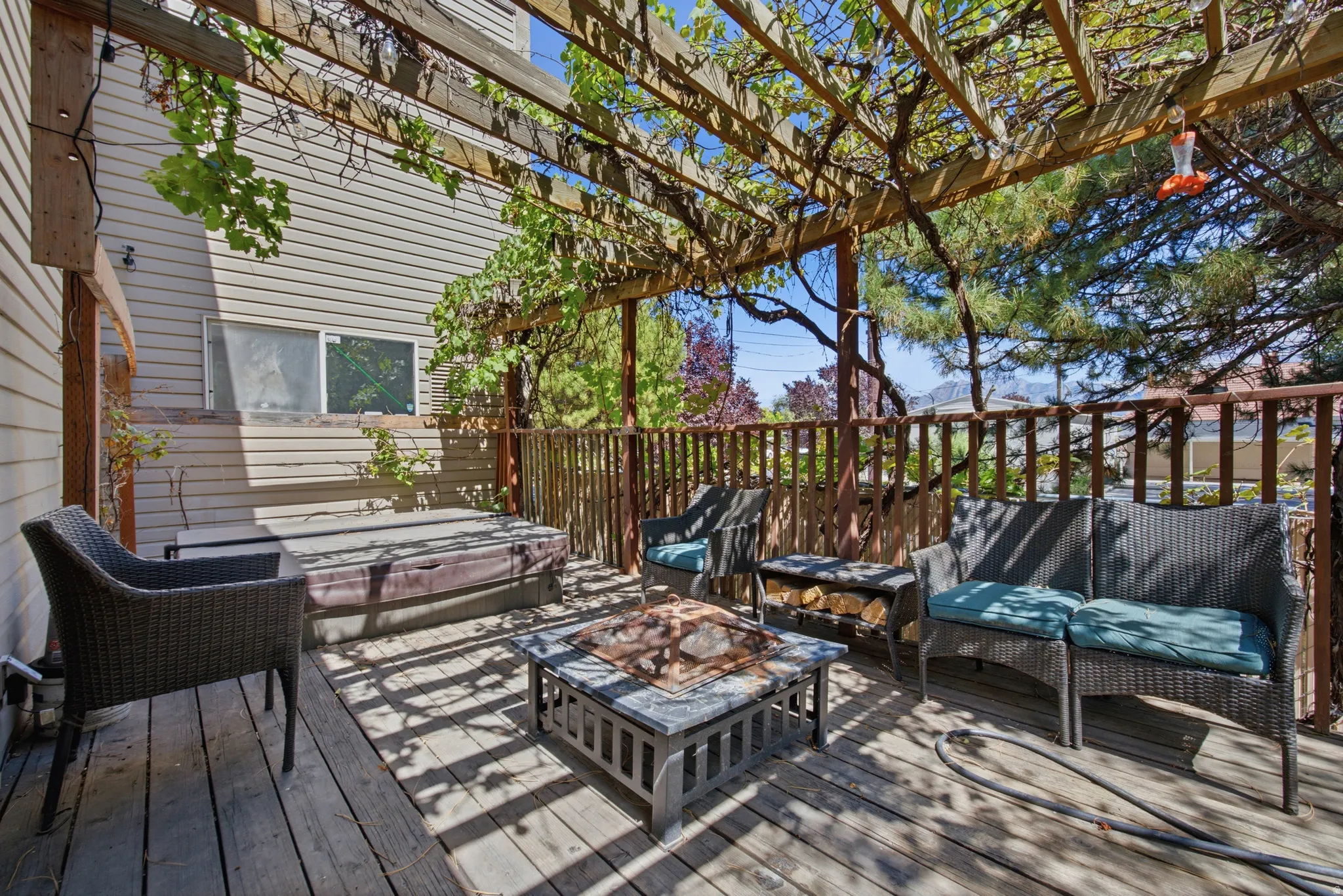 Wood-finish deck with a built-in hot tub, an overhead pergola, and wood railing
