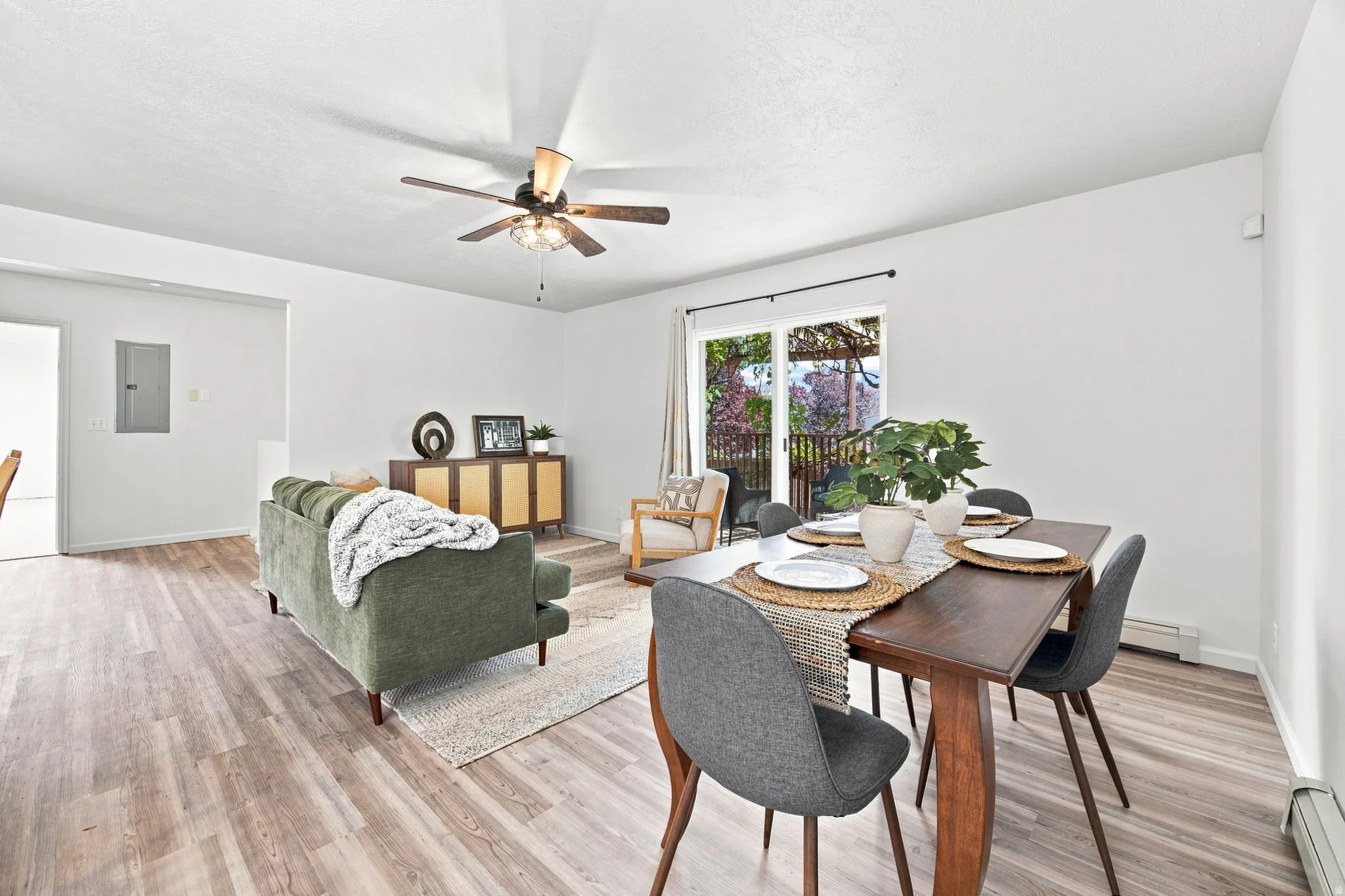 Open-concept living area with wood-finish flooring, a ceiling fan, and sliding glass doors leading to an outdoor space