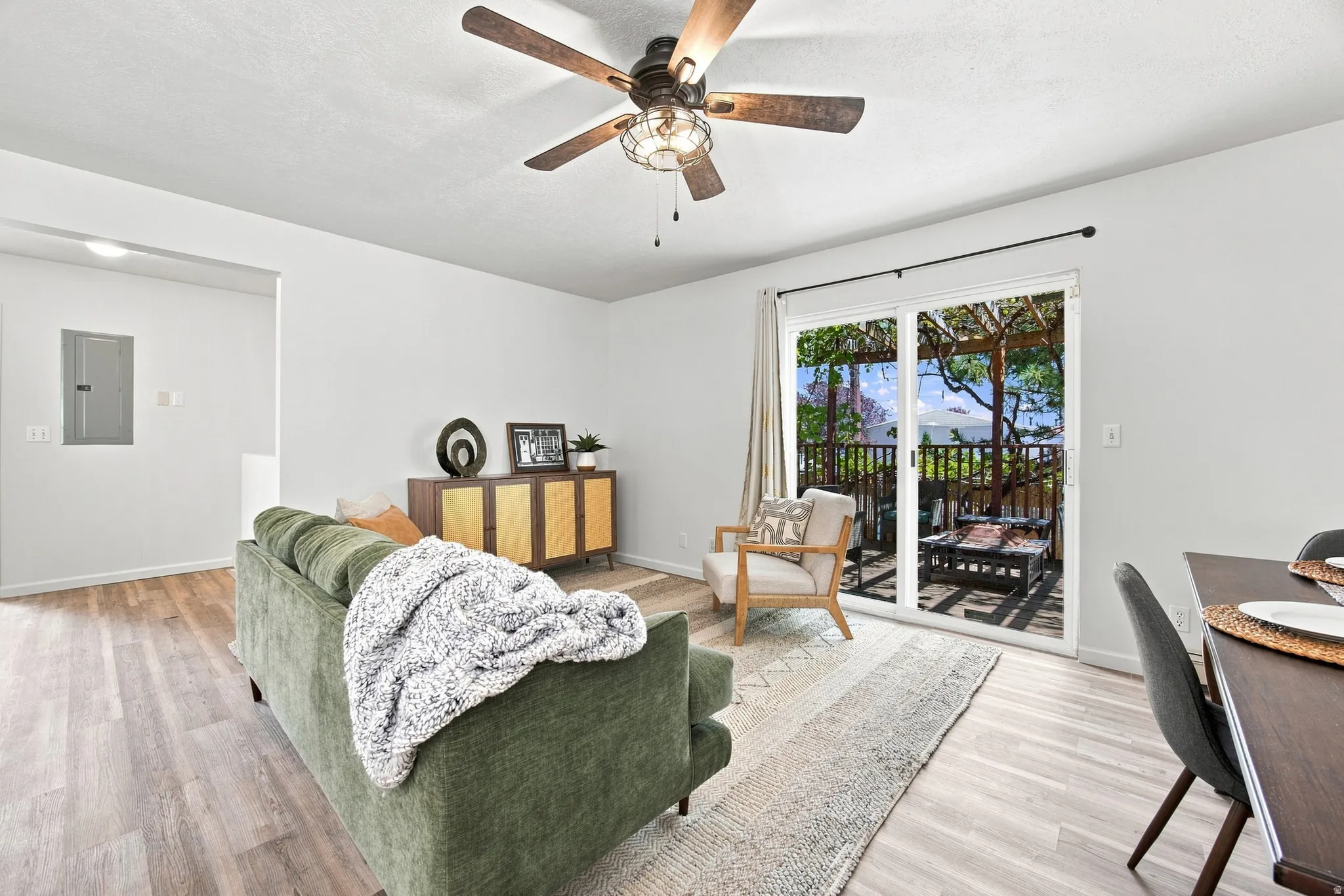 Hardwood-finish flooring, sliding glass door, overhead fan with integrated lighting, and white walls