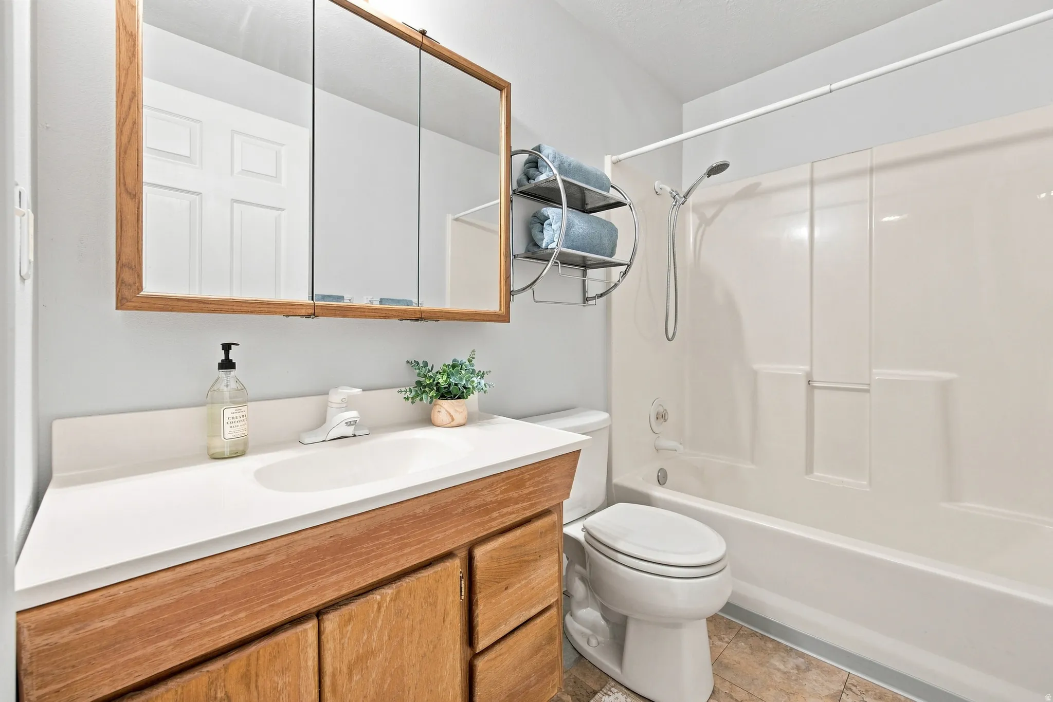 Bathroom with a wood-finish vanity, integrated sink, and a mirrored medicine cabinet