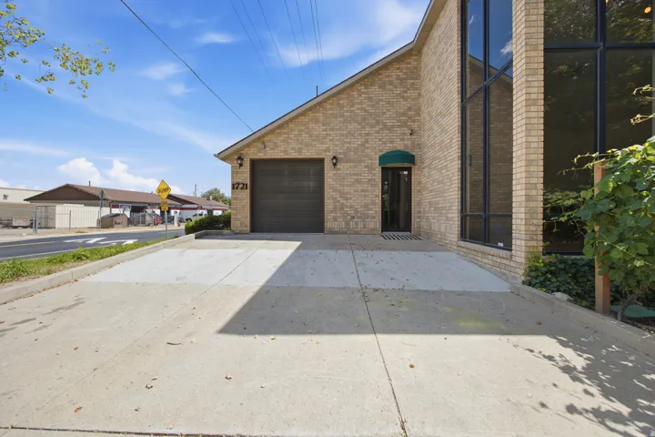 Brick exterior with large format windows, a dark garage door, and a covered entry