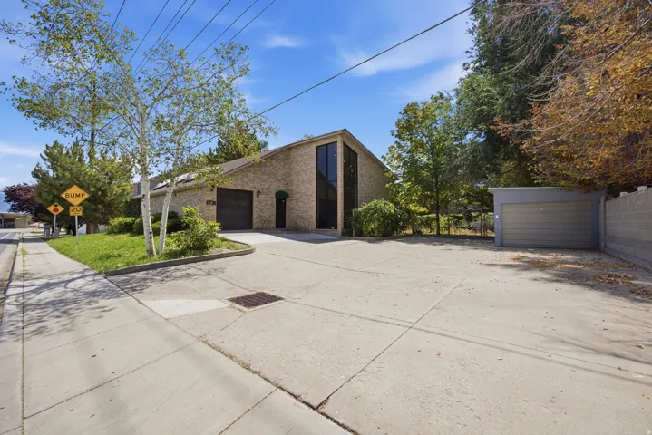 Brick exterior, attached garage, detached garage, concrete driveway, and mature landscaping