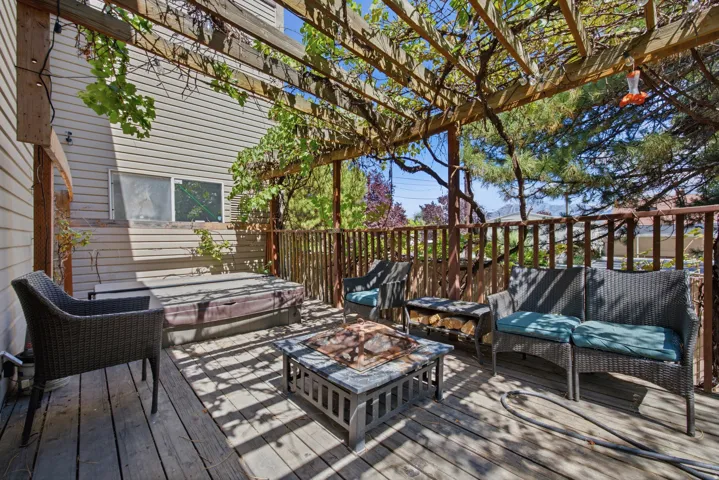 Wood-finish deck with a built-in hot tub, an overhead pergola, and wood railing