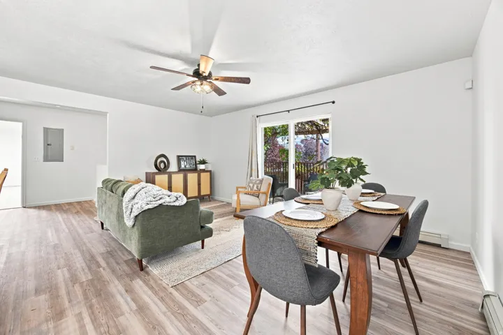 Open-concept living area with wood-finish flooring, a ceiling fan, and sliding glass doors leading to an outdoor space